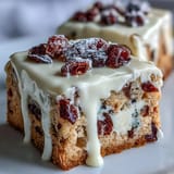 Homemade Cranberry Bliss Bars featuring creamy frosting, cranberries, and white chocolate on a plate.