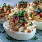 Platter of chilled Million Dollar Deviled Eggs with creamy filling and paprika dusting.