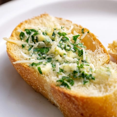 Golden, crispy Garlic Bread slices with melted butter and herbs, ready to serve alongside a bowl of spaghetti.