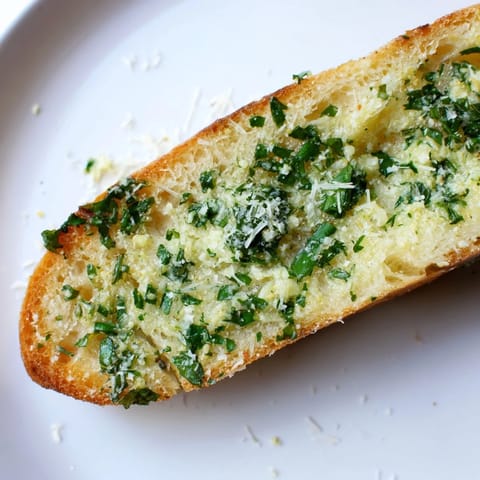 A close-up view of homemade Garlic Bread, showcasing crunchy edges and fresh parsley specks on warm, buttery bread.