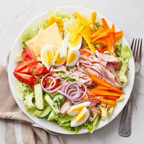 Classic Chef Salad arranged on a platter, featuring colorful vegetables like tomatoes, cucumber, and carrots alongside crisp romaine and iceberg lettuce for a hearty meal.