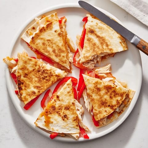 Freshly cooked chicken quesadilla cut into wedges, served with a small bowl of salsa and creamy guacamole.