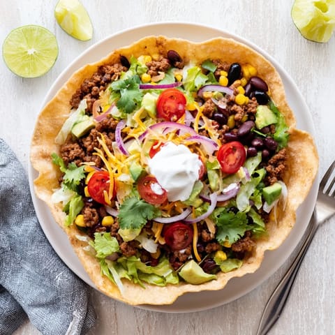 Crispy golden tortilla bowl filled with seasoned beef, black beans, and melted cheddar for a hearty Taco Salad.