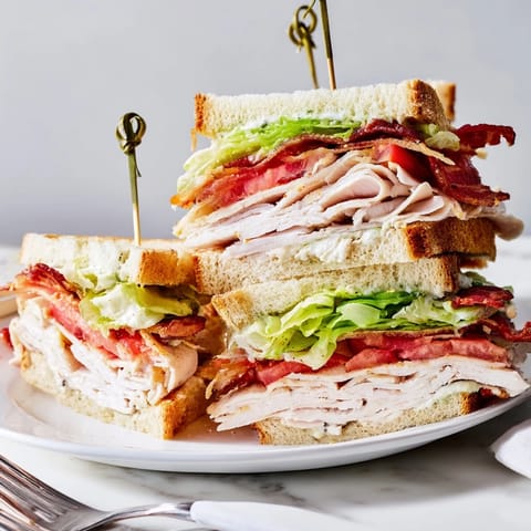 Golden brown toasted bread reveals layers of turkey, bacon, and fresh lettuce in a classic Turkey Club Sandwich.