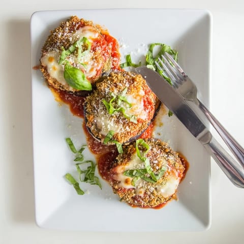 Golden, crispy breaded eggplant slices layered with rich tomato sauce and melted mozzarella for classic Eggplant Parmesan.