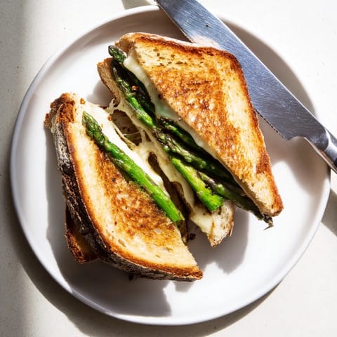 Asparagus & Brie Grilled Cheese sandwich rests on a wooden board, ready for a light lunch or cozy dinner.