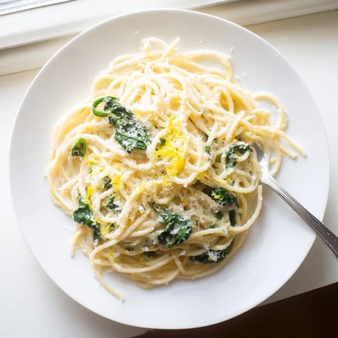 Steaming bowl of Creamy Lemon Spinach Spaghetti topped with extra Parmesan and lemon zest, ready to serve as a comforting vegetarian main dish.  