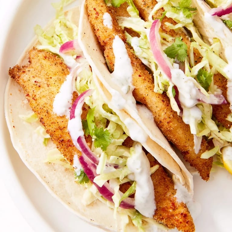 Flaky white fish nestled in warm tortillas with crunchy slaw and a squeeze of lime, ready to serve.