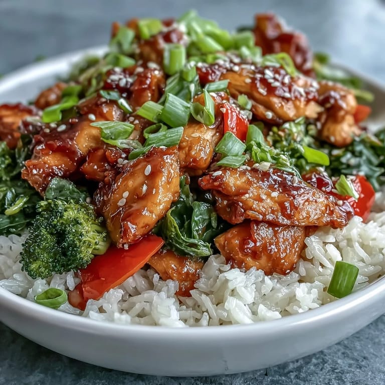 Golden glazed chicken in a honey garlic sauce served in a bowl with fluffy rice and colorful vegetables for a complete meal.