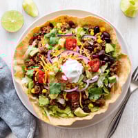 Crispy golden tortilla bowl filled with seasoned beef, black beans, and melted cheddar for a hearty Taco Salad.