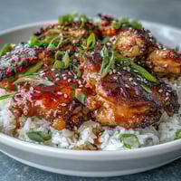Honey Garlic Chicken with Rice in a crockpot, served over fluffy jasmine rice with sesame seeds and green onions.